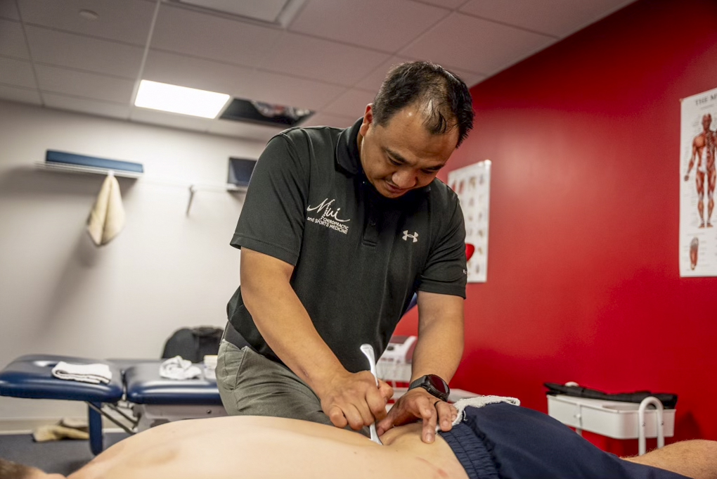 Sports chiropractor performing Graston Technique on professional athlete"